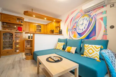 a living room with a blue couch and a clock on the wall at Бургаски вечери Burgas nights in Burgas City