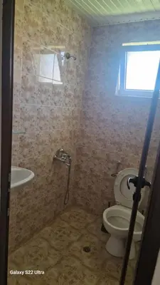 a bathroom with a shower and a toilet and a window at Къща за гости Ravda in Ravda