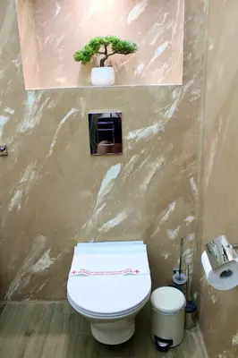 a bathroom with a toilet and a plant on the wall at Cozy by the Sea in Burgas City