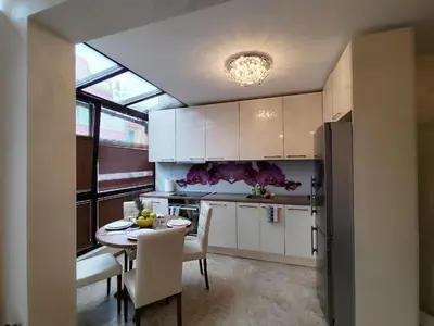 a kitchen with white cabinets and a table with chairs at Villa Alva in Pomorie