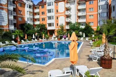 a pool with chairs and an umbrella next to a building at Sea Diamond 2 in Sunny Beach