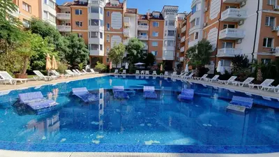 a large swimming pool with blue chairs and buildings at Sea Diamond 2 in Sunny Beach