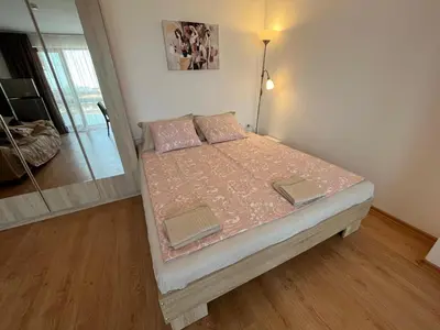 a small bedroom with a bed with a pink comforter at Apartamenty na Zielonych Wzgórzach in Sunny Beach