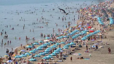 a crowd of people on a beach with umbrellas at Студио in Burgas City