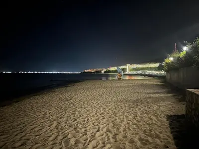 a sandy beach at night with lights on the water at Amartmán přímo u moře - Elenite až 5 osob in Sveti Vlas