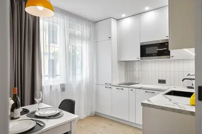 a kitchen with white cabinets and a table with a wine glass at Sea Moreto Apartment 3 in Burgas City