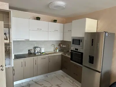 a kitchen with white cabinets and a stainless steel refrigerator at Apartment Tuthon in Pomorie