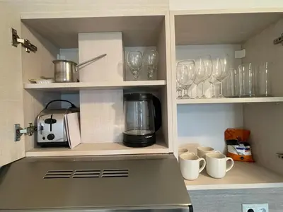 a kitchen with cups and wine glasses on shelves at Fortuna Cape 4 apartment in Byala