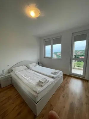 a white bedroom with a bed and two windows at Fortuna Cape 4 apartment in Byala