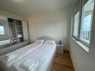 a bedroom with a large white bed with a large window at Fortuna Cape 4 apartment in Byala