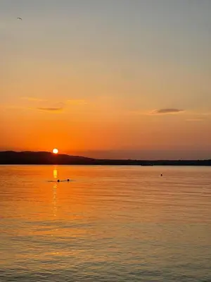 a sunset over a body of water with a boat at Amara Holiday Santa Marina, Sozopol in Sozopol