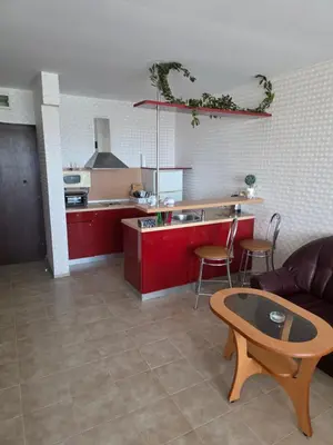 a kitchen with red cabinets and a table and a couch at Apartament Hotel Miramar Palace in Sunny Beach