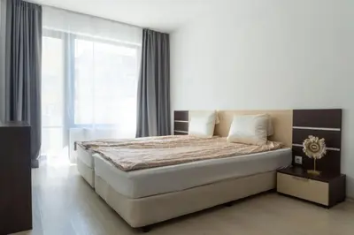 a bedroom with a large bed and a large window at Делукс Апартамент Лазур Поморие in Pomorie