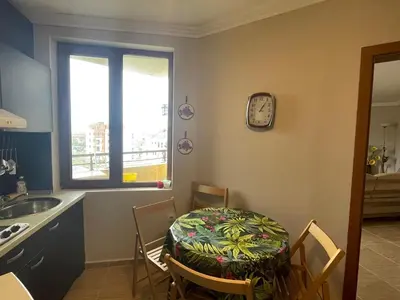 a kitchen with a table and a clock on the wall at Quiet 1-Bed Flat in Antonia Complex by Flat Mаnager in Sveti Vlas