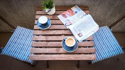 a newspaper and a cup of coffee on a wooden table at Studio Comfort Blue in Primorsko