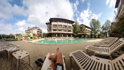 a person laying on a lounge chair in front of a pool at Studio Comfort Blue in Primorsko
