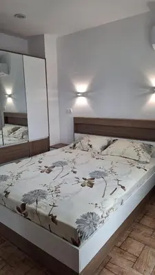 a bedroom with a large bed with a white wall at Апартамент ReLax Китен in Kiten