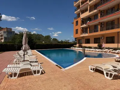 a group of lounge chairs and a swimming pool in front of a building at BW - Happy 67 in Sunny Beach