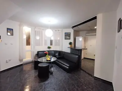 a living room with a black leather couch and a table at Мезонет в Гръцката Махала in Varna City