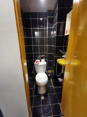 a black tiled bathroom with a toilet and a sink at Мезонет в Гръцката Махала in Varna City