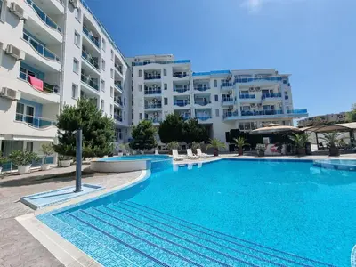 a swimming pool in front of a large apartment building at Odisei Large Studio in Nesebar