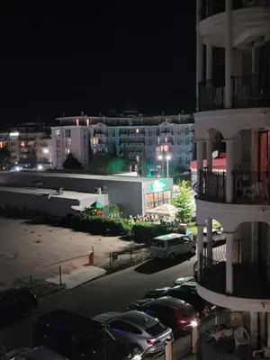 a city at night with cars parked in a parking lot at Royal Sun Apartment in Sunny Beach