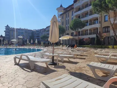 a group of chairs and an umbrella next to a pool at Royal Sun Apartment in Sunny Beach