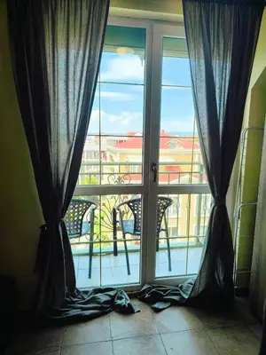 a window with curtains and a view of a balcony at Golden Hermes, Studio z basenem in Sunny Beach