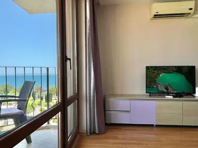 a living room with a television and a balcony at Prestige Fort Aparthotel - Private apartment - BSR - 3 in Sveti Vlas