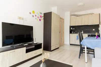 a kitchen with a table and a large tv in a room at Marea 2 in Pomorie