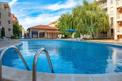a large blue swimming pool with two buildings at Chocolate Apartment on Sunny Day 6 Complex in Tŭnkovo