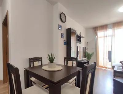 a dining room with a table and chairs and a clock at Chocolate Apartment on Sunny Day 6 Complex in Tŭnkovo