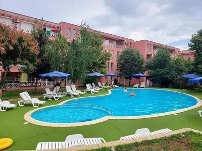 a swimming pool with chairs and umbrellas in front of a building at Chocolate Apartment on Sunny Day 6 Complex in Tŭnkovo