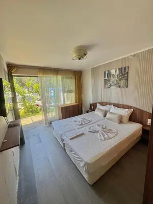 a bedroom with a large bed and a large window at Иглика Апарт Несебър in Nesebar