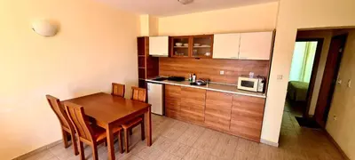 a kitchen with a wooden table and a microwave at Тристаен просторен апартамент с две отделни спални in Sunny Beach