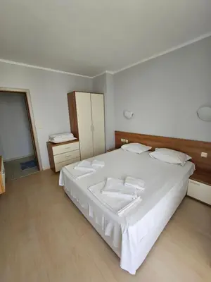 a bedroom with a large white bed with towels on it at Тристаен просторен апартамент с две отделни спални in Sunny Beach