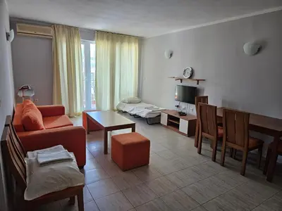 a living room with a couch and a table at Тристаен просторен апартамент с две отделни спални in Sunny Beach