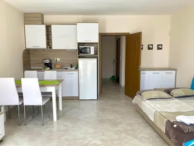 a kitchen with a bed and a table in a room at Apartments in Villas Apolon in Sozopol