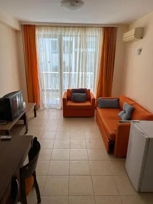 a living room with an orange couch and a tv at 2 Room Apartment Royal Sun Sunnybeach in Sunny Beach