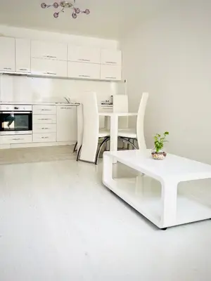 a white kitchen with a table and white chairs at Park suite in Burgas City