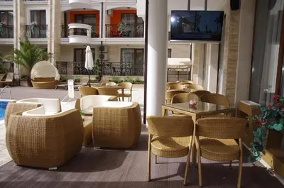 a patio with chairs and tables and a tv on a building at Patrick's apartments - Harmony Palace in Sunny Beach