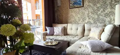 a living room with a white couch and a table at Patrick's apartments - Harmony Palace in Sunny Beach