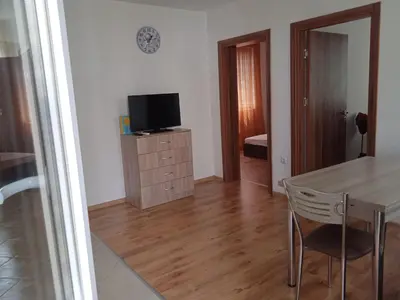 a living room with a table and a television on a cabinet at Тристаен апартамент в Бяла комплекс Атлантик in Byala