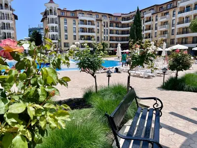 a park bench in front of a building with a pool at Apartament Royal Sun Romantic - 5 min to the beach in Sunny Beach