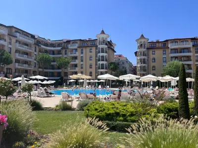 a hotel with a swimming pool with chairs and umbrellas at Apartament Royal Sun Romantic - 5 min to the beach in Sunny Beach