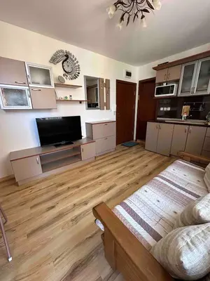 a large living room with wooden floors and a flat screen tv at Свети Влас комплекс Викторио in Burgas City