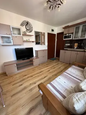 a large living room with wooden floors and a flat screen tv at Свети Влас комплекс Викторио in Burgas City