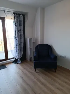 a living room with a blue chair and a window at 2 Zimmerwohnung in Shkorpilovtsi