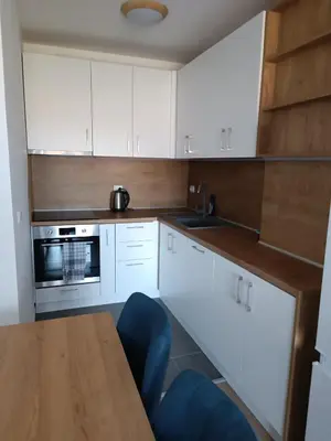 a kitchen with white cabinets and a wooden table at 2 Zimmerwohnung in Shkorpilovtsi