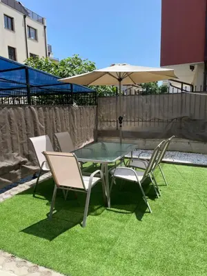 a table and chairs and an umbrella on some grass at Sarafovo Summer 1 - Relaxing Apartment Near Beach in Sarafovo
